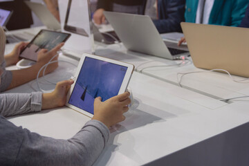 Customers select tablets and laptops in the electronics store
