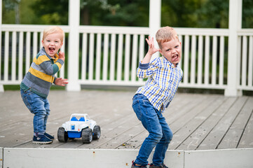 Two Boys Making Funny Faces and Playing Outdoors with Toy Car