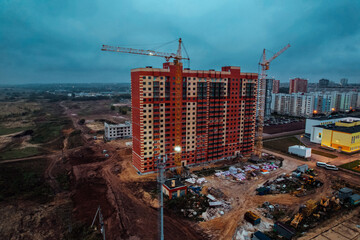 Construction site background. Hoisting cranes and new multi-storey buildings. Industrial background. Building construction site work against blue sky monolithic technology.