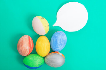 Colorful Easter eggs with speech bubble on green background. top view