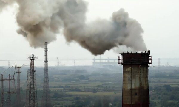 Large pipes with thick smoke. Dirty factory chimney blowing huge puffs of smoke into air. Environmental poisoning