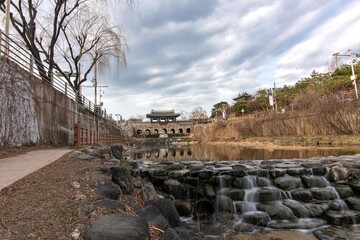 Snapped this stunning long-exposure shot of Hwaseong Fortress' Hwahongmun in Suwon this March. The flowing water and traditional gate under a cloudy sky are mesmerizing!
