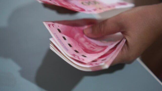 China's economy, Renminbi in global finance or world trade. Counting yuan banknotes Chinese currency (Renminbi or RMB) featuring 100-yuan banknote with Mao Zedong's portrait, slow clip