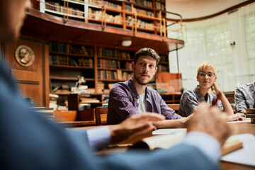 University students listening to professor in historic library