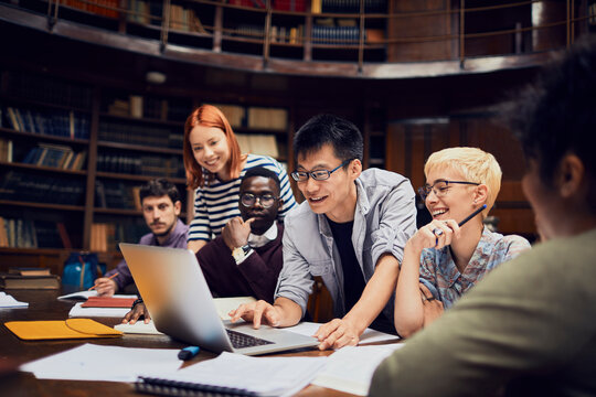 Diverse group of college students collaborating on laptop in library