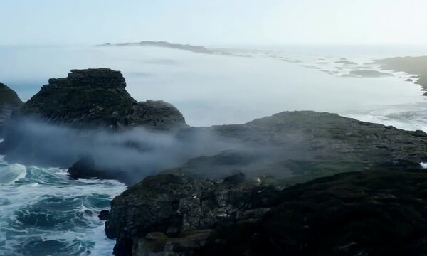 Beautiful rocky coastline of Montara, California, USA. Thick fog slowly moving on city from waters of Pacific. Top view. Vertical