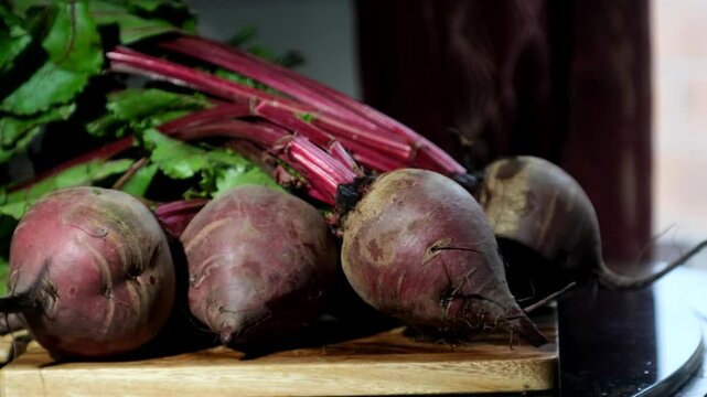 Freshly harvested beetroots rest on a wooden surface, their deep purple skins rich with earthy texture.