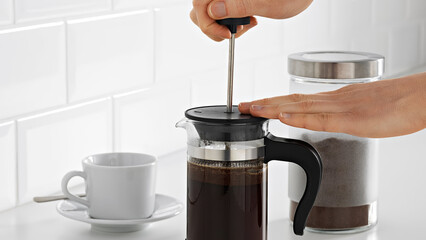 Closeup of a person preparing coffee in a french press coffee maker.
