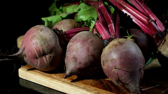Freshly harvested beetroots rest on a wooden surface, their deep purple skins rich with earthy texture.