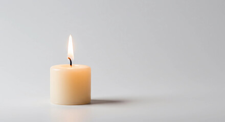  single candle burning softly in the center of a plain white background