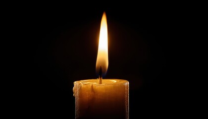 A single candle burning brightly in the dark with dripping wax illuminating the shadows around it