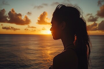 A woman watches the sunset over the tranquil ocean waters