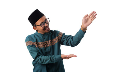 Asian Muslim man gesturing at copy space with an open palm to the side, presenting empty space for advertisement or promotion, smiling confidently, isolated on a white background