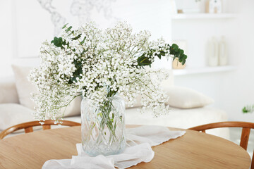 Bouquet of beautiful gypsophila flowers and eucalyptus branches in vase on table indoors