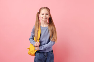 Cute schoolgirl with backpack on pink background