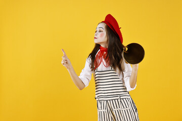 Cute girl dressed like mime with megaphone pointing at something on yellow background, space for...