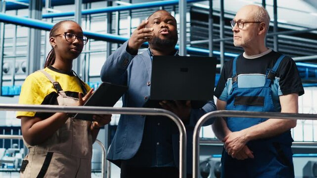 Smart factory manager discussing with employees automated workflow implementation. Supervisor overseeing industrial plant talks with workers, integrating sensors into production, camera A