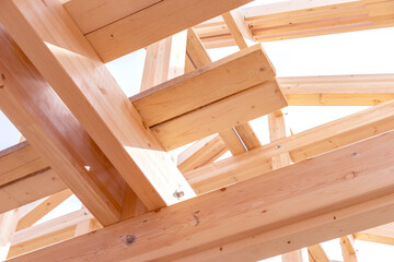 Fragment house under construction. Wooden frame of building close-up. Beams building frame are connected to each other. House under construction made of planks. Erection of building made of lumber