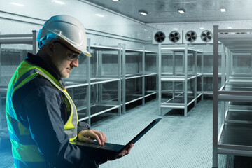 Man contractor in cold storage warehouse. Industrial refrigerator with metal racks. Freezer...