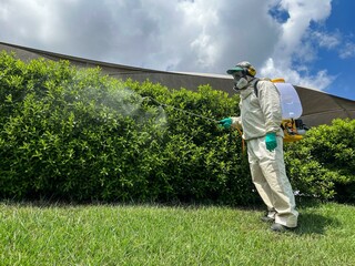 A dedicated pest control worker in full protective gear, including a respirator and protective...