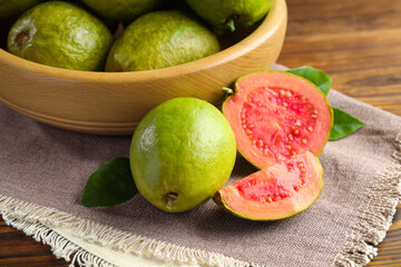 Fresh cut and whole guava fruits on wooden table