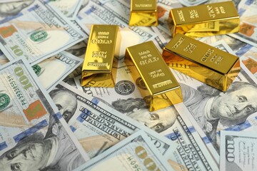 Shiny gold bars on dollar banknotes. Space for text