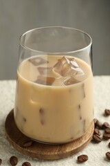 Coffee cream liqueur in glass and beans on white textured table, closeup