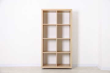Empty wooden shelving unit near white wall indoors