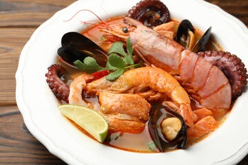 Delicious seafood soup in bowl on wooden table, closeup