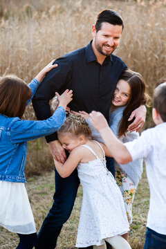 Dad being tackled by his children, having fun together outside