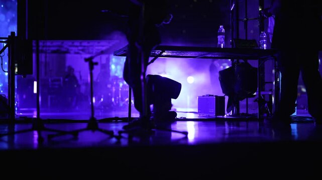 backstage crew walk by on stage