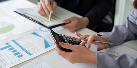 Calculation and Financial Analysis. A business professional using a calculator while discussing...