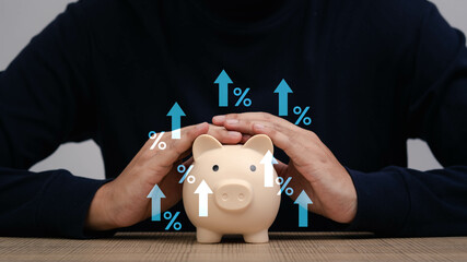 A person safeguarding a piggy bank with hands over it, symbolizing financial growth and savings...