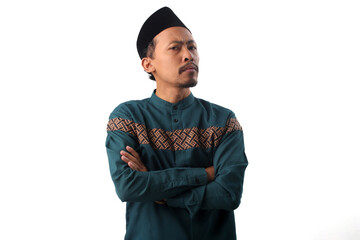 Thoughtful Asian Muslim man standing with a pensive expression, hands folded as if deep in thought,...