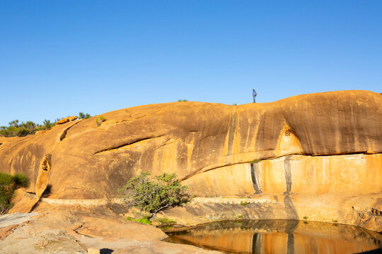 human figure atop granite rock formation in the wheatbelt