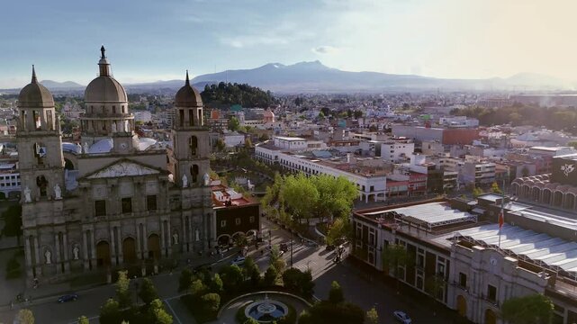 Aerial view of Toluca Cathedral in Mexico at sunset with Toluca volcano in the background. Drone camera approaches and orbits the church facade