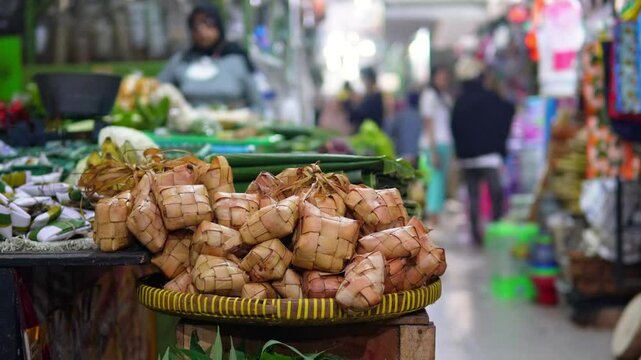 stack of ketupat on a bamboo tray at a traditional market
