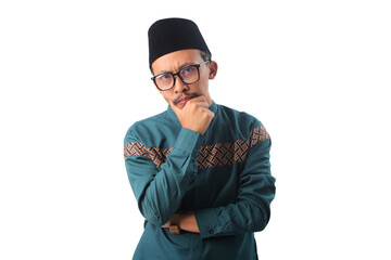 Pensive Asian Muslim man resting his hand on his chin, deep in thought while looking at the camera, isolated on a white background