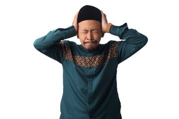 Stressed Asian Muslim man with eyes closed, holding his head, struggling to control his emotions and resist temptations while fasting during Ramadan, isolated on a white background