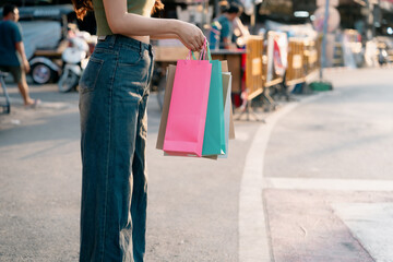Obraz premium Beautiful young woman holding shopping bags during sale. She is dressed stylishly and enjoys shopping to the fullest. There is fun and excitement of shopping therapy.