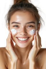 portrait of young asian beautiful smiling female touching cheeks with fingers as if applying skincare cream