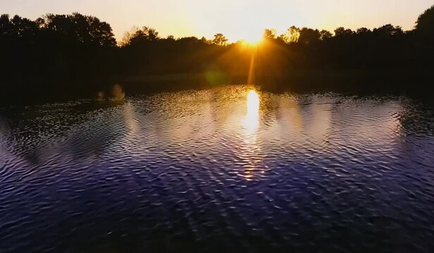 Rippling lake water with shade of trees in sundown light