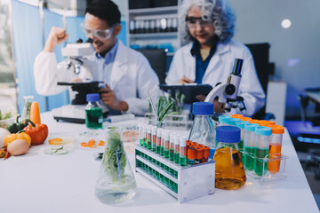 Team Asian scientists in a lab conducting food research using a microscope and lab equipment,...