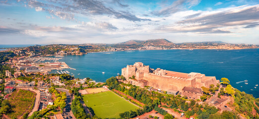 Naklejka premium Panoramic view from flying drone of Aragonese Castle of Baia with football stadium, Italy, Europe. Captivating morning seascape of Mediterranean sea. Traveling concept background.