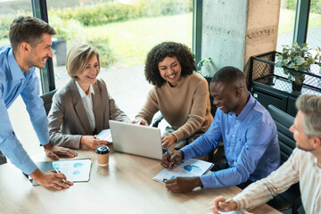 Successful businesspeople working in a coworking space working with laptop discussing strategy and...