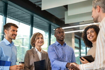 Team of businessmen shaking hands while standing in an office, finishing up a meeting