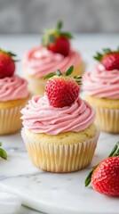 Delicious strawberry cupcakes with pink frosting and fresh strawberries topping