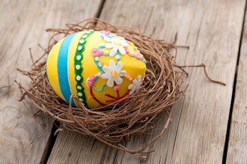 Obraz premium Decorative Easter egg in a nest on wooden table