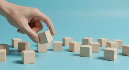 Hand Arranging Beige Wooden Cubes in Light Blue Background Achieving Minimalist and Conceptual Design