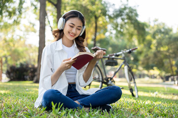 Young asian woman relaxing reading book sitting at public park life style outdoor. Happy female...